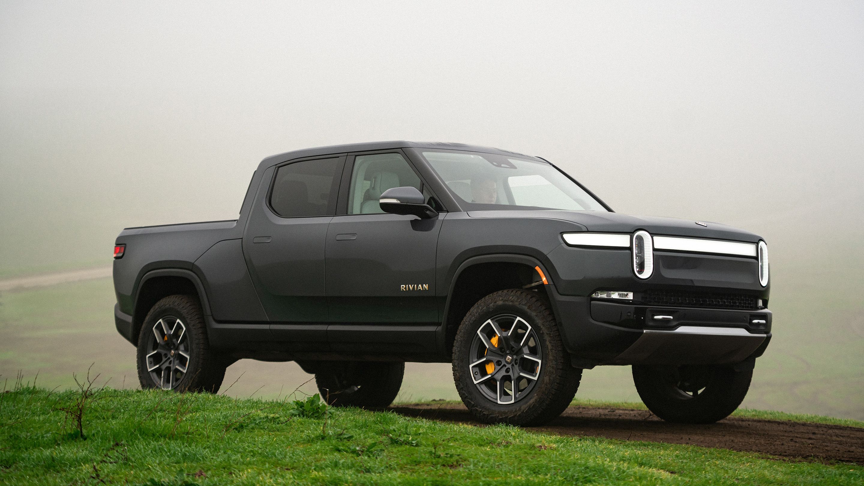 Grey Rivian R1T electric truck on grassy path