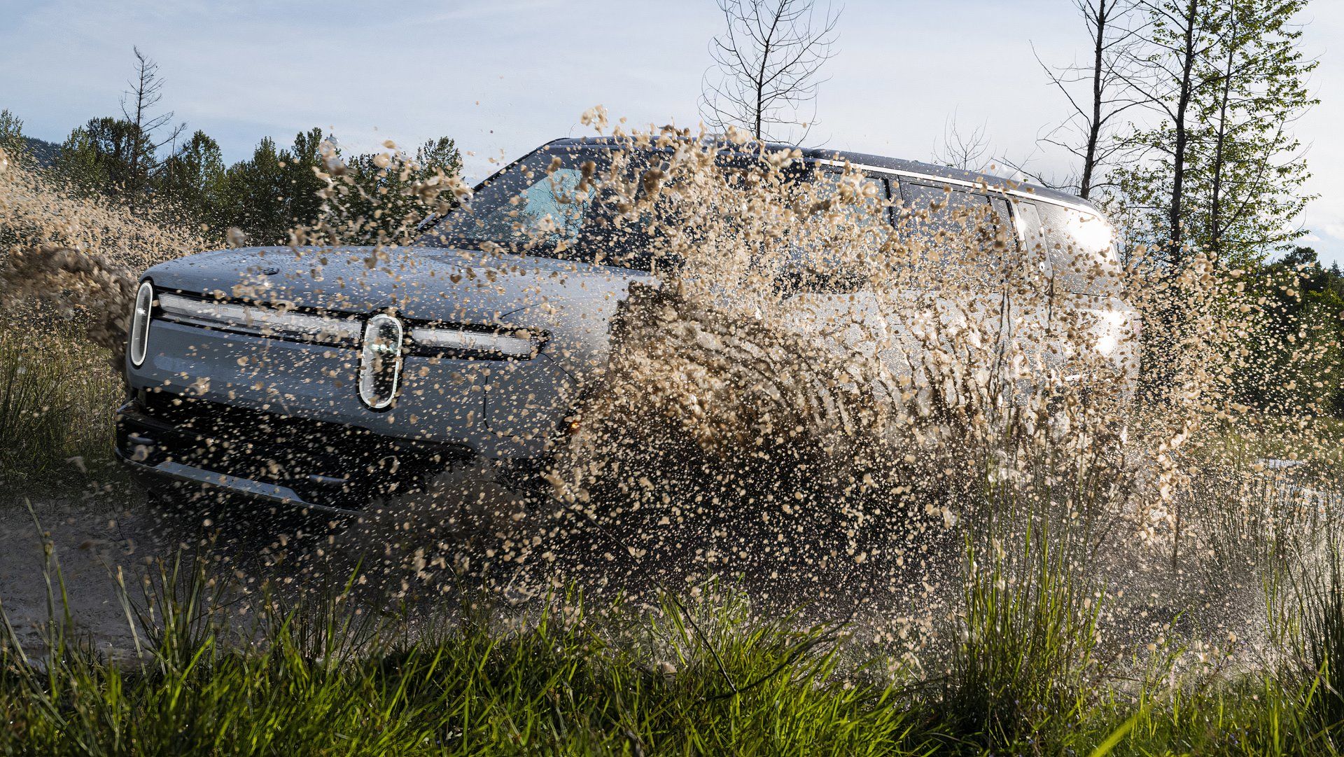 Rivian R1S, front quarter view closeup, splashing mud, obscured from view