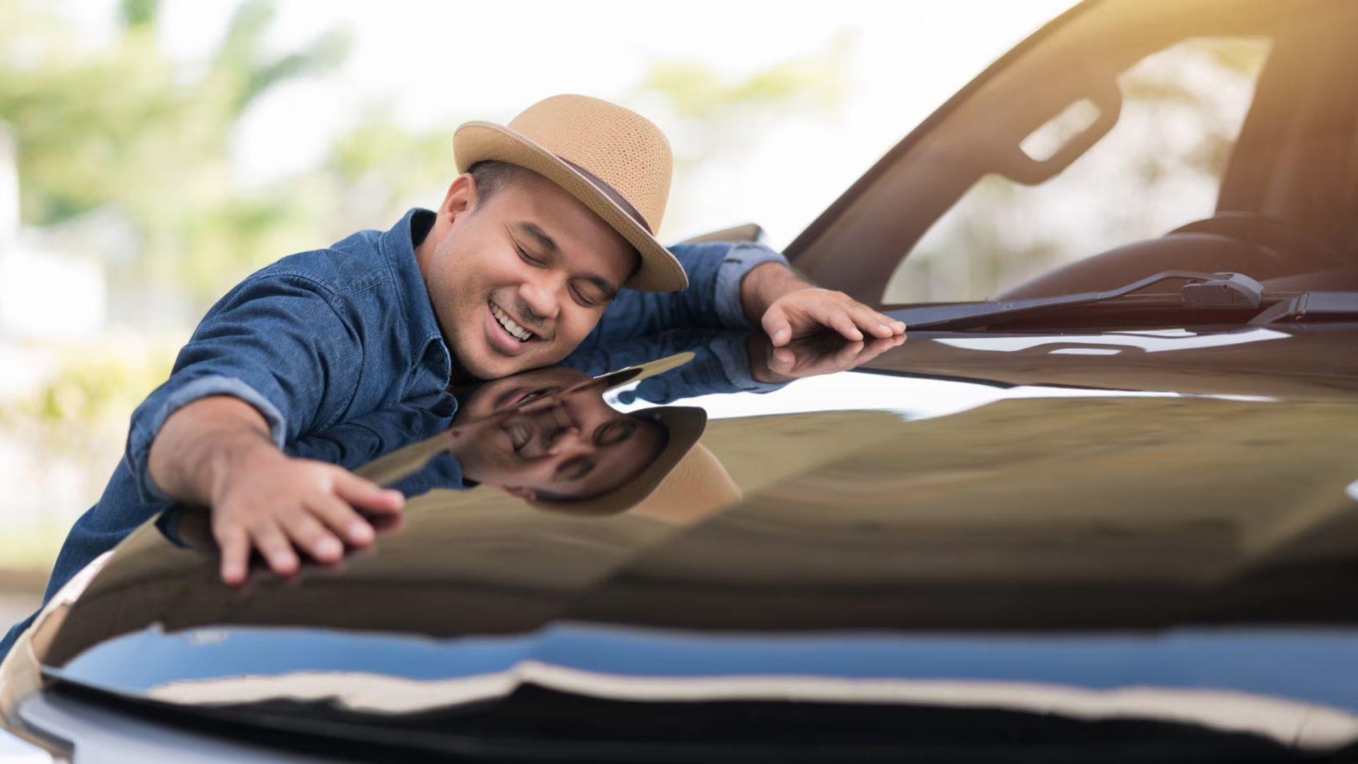 A Guy Smiling And Hugging Car