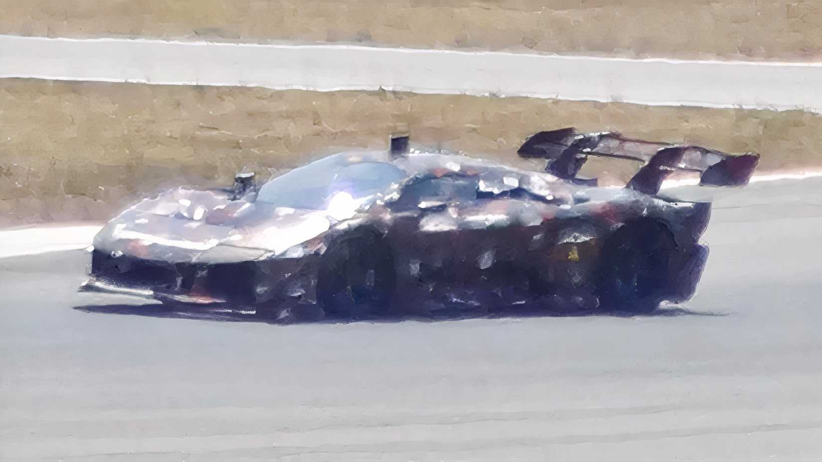 A camouflaged Ferrari F80 prototype with a massive rear wing undergoing high-speed testing on the track.